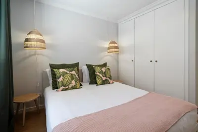 a bedroom with a white bed with green and pink pillows at Solar da Fontinha by An Island Apart in Santa Cruz