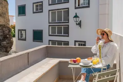 a woman sitting at a table on a balcony at Solar da Fontinha by An Island Apart in Santa Cruz
