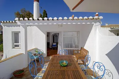 a patio with a wooden table and chairs and a lighthouse at 602 Casa Alma Mar in Luz