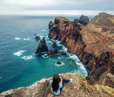 a woman sitting on a cliff looking at the ocean at Casa da Avó in Machico