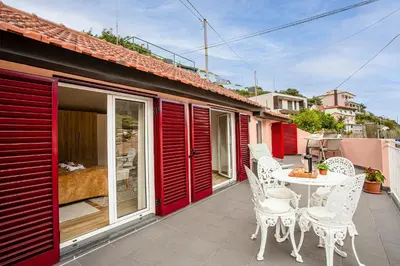 a patio with white chairs and a table on a balcony at Casa da Avó in Machico