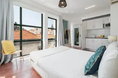 a bedroom with a white bed and a large window at Pelourinho Apartments by An Island Apart in Funchal