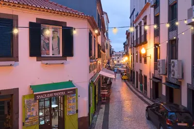 a narrow street with buildings and a car parked on the road at Pelourinho Apartments by An Island Apart in Funchal