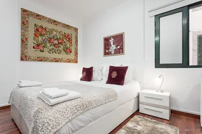 a white bedroom with a bed and a picture on the wall at Pelourinho Apartments by An Island Apart in Funchal