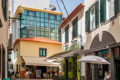 a city street with buildings and tables and umbrellas at Pelourinho Apartments by An Island Apart in Funchal