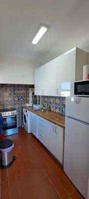 a kitchen with white cabinets and a brown tile floor at Seaview Apartment 100m from beach in Luz