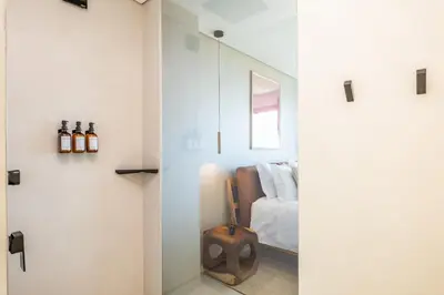 a room with a bed and a glass door with a mirror at House of Cork and Ivy - By WeHost in Câmara de Lobos