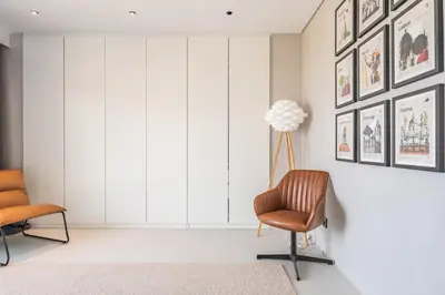 a living room with two chairs and pictures on the wall at House of Cork and Ivy - By WeHost in Câmara de Lobos
