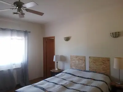 a bedroom with a bed and a ceiling fan at Chambres Guest house in Bensafrim