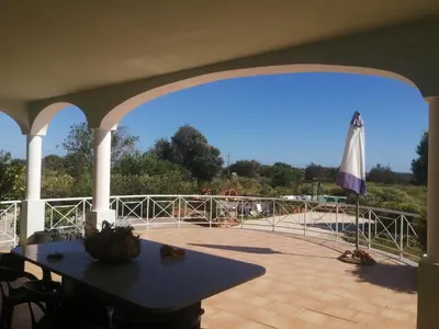 a patio with a table and an umbrella at Chambres Guest house in Bensafrim