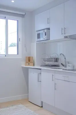a white kitchen with white cabinets and a window at Casal da Penha Apartments in Funchal