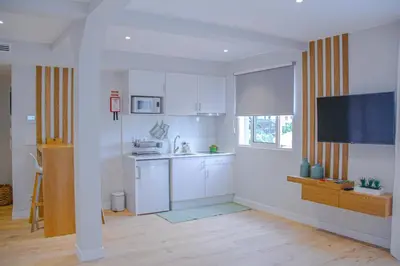 a kitchen with white cabinets and a television in it at Casal da Penha Apartments in Funchal
