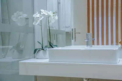a bathroom sink with a vase with flowers in it at Casal da Penha Apartments in Funchal