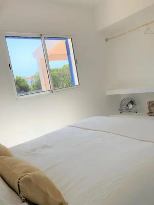 a white bedroom with a bed and two windows at Casa 70 - Surfboard included in Aljezur