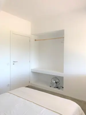 a white bedroom with a bed and white shelves at Casa 70 - Surfboard included in Aljezur