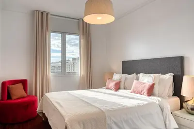 a bedroom with a large bed and a red chair at Encarnação Funchal, a Home in Madeira in Funchal