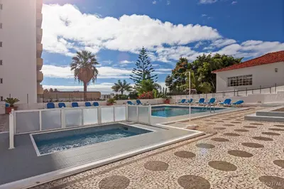 a swimming pool with blue chairs next to a building at Casa Branca Apartments by TrIp2Portugal in Funchal
