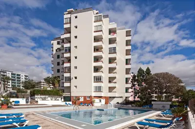 a hotel with a swimming pool and a tall building at Casa Branca Apartments by TrIp2Portugal in Funchal
