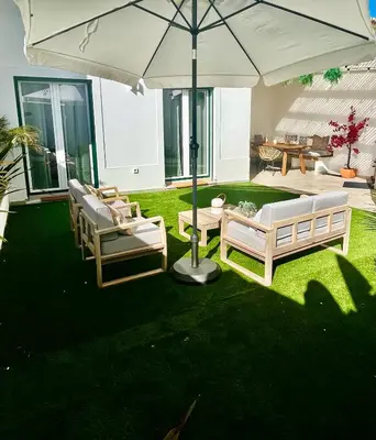 a patio with two chairs and an umbrella at Nōhō house in Carrapateira