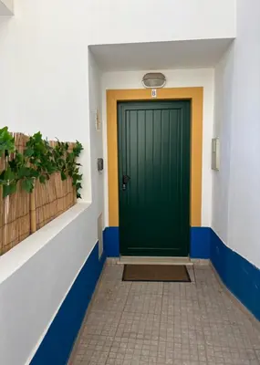 a green door in a hallway with a tile floor at Nōhō house in Carrapateira