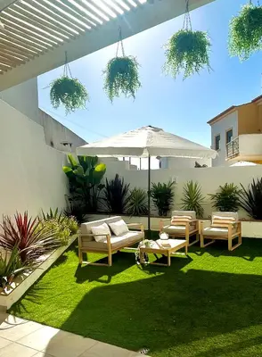 a patio with chairs and an umbrella and grass at Nōhō house in Carrapateira