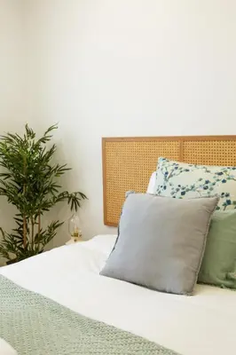 a bed with white sheets and pillows and a plant at Nōhō house in Carrapateira