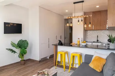 a living room and kitchen with a couch and yellow stools at Alegria Flat by An Island Apart in Funchal