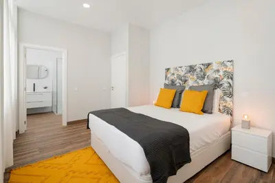 a white bedroom with a large bed with yellow pillows at Alegria Flat by An Island Apart in Funchal