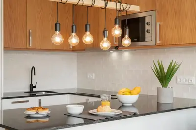 a kitchen with a counter with bowls of fruit and lights at Alegria Flat by An Island Apart in Funchal