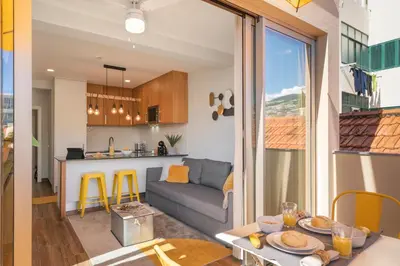a living room and kitchen with a couch and a table at Alegria Flat by An Island Apart in Funchal