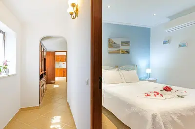 a bedroom with a bed with white sheets and flowers on it at Bela casa na Costa Vicentina in Aljezur