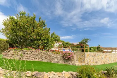 a garden with a stone retaining wall and flowers at Bela casa na Costa Vicentina in Aljezur