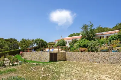 a garden with a stone wall and a building at Bela casa na Costa Vicentina in Aljezur