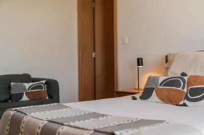 a bedroom with a bed and a couch and a chair at Casinha dos Canhas by An Island Apart in Ponta do Sol