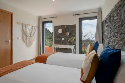 a hotel room with two beds and a window at Casinha dos Canhas by An Island Apart in Ponta do Sol