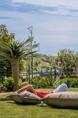 a woman laying on the grass reading a book at Casinha dos Canhas by An Island Apart in Ponta do Sol