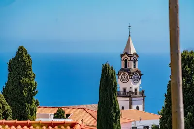a building with a clock tower with a steeple at OurMadeira - Arco Sun in Arco da Calheta