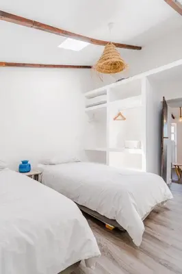 two beds in a bedroom with white walls and wood floors at Casa Alfambras - Holiday Cottage in Aljezur by Lisbeyond in Aljezur