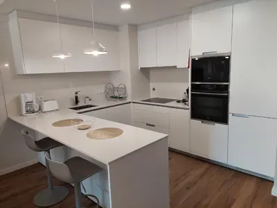 a kitchen with white cabinets and a counter with two sinks at Stunning Lobos View in Câmara de Lobos