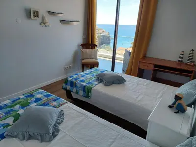 a bedroom with two beds and a view of the ocean at Stunning Lobos View in Câmara de Lobos