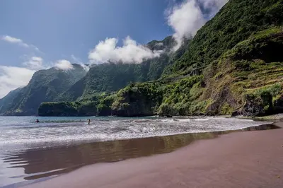 a beach with people in the water and a mountain at Casa da Portada in Seixal