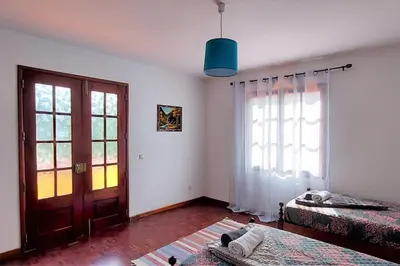 a room with two beds and a door and a window at Gomes house in Ponta do Sol