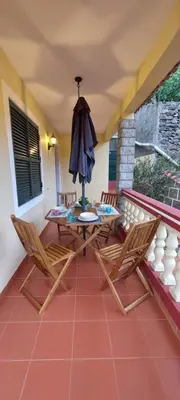 a patio with a table and chairs and an umbrella at Gomes house in Ponta do Sol