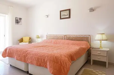 a bedroom with a bed with an orange comforter at Ramalhete panoramic view apartment in Luz