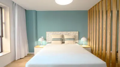 a bedroom with a large white bed with blue walls at Marina Club Studio Traveller Hideaway in Funchal