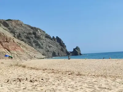 a beach with people and the ocean and cliffs at Lovely 1 Bedroom apartment in Praia da Luz in Luz