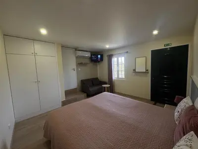 a bedroom with a bed and a couch and a television at A Toca in Santana