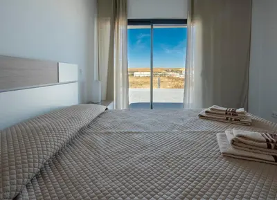a bedroom with a large bed with a large window at Sunset House in Vila do Bispo