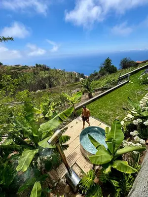 a man walking down a walkway in a garden at Meerblick - 3-Bett Villa mit Terrassen & Hot-Tub in Fajã da Ovelha
