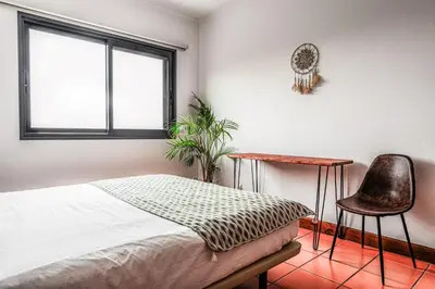 a bedroom with a bed and a chair and a window at Meerblick - 3-Bett Villa mit Terrassen & Hot-Tub in Fajã da Ovelha